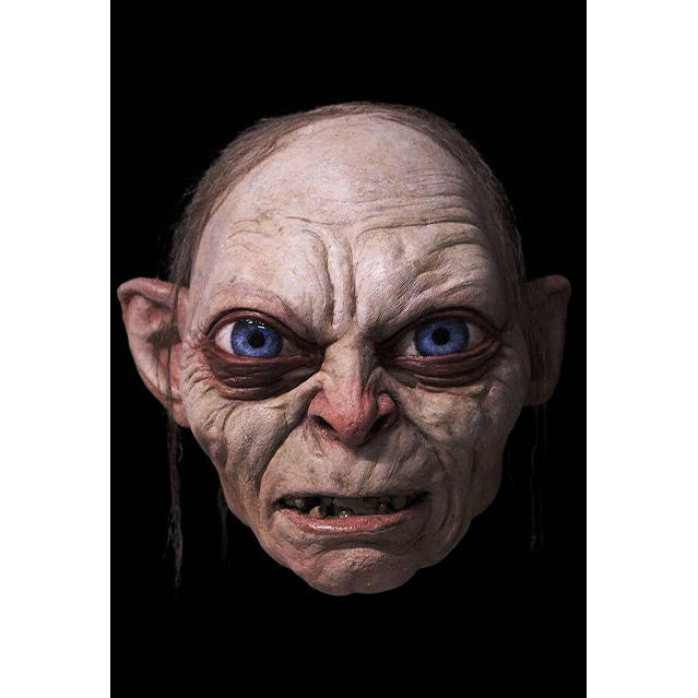 Mask, front view. Black background. Gollum, wrinkled grimacing face, large bright blue eyes, mouth slightly open, crooked teeth. stringy, sparse brown hair.