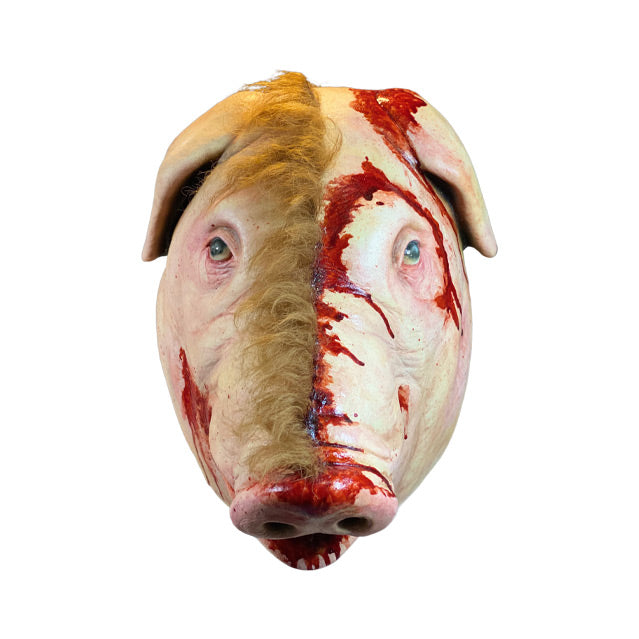 Mask, front view.  Pig face, brown fur on right side, skinned on left side, pink and bloody around ear, nose and mouth