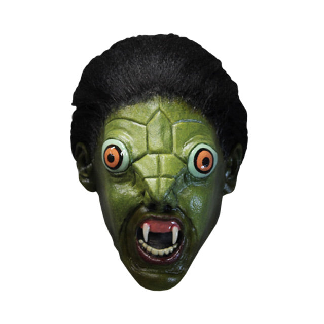 Mask, front view.  Green reptile face, long black hair pulled back in a ponytail, large orange eyes, small nose, open mouth with 2 large fangs and showing bottom teeth. 