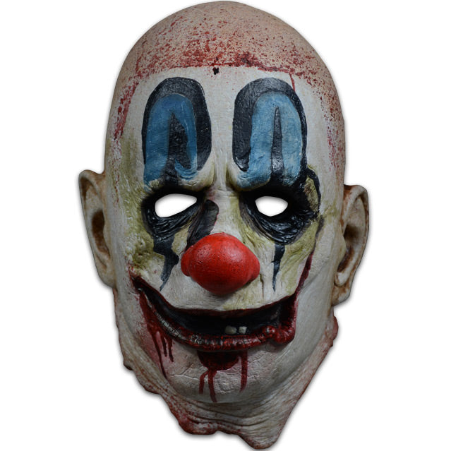 Mask, front view.  Bald head, blood spattered, white, dirty clown makeup.  Blue painted above black-rimmed eyes, large red clown nose, red clown mouth open with 2 teeth showing, blood dripping from mouth.