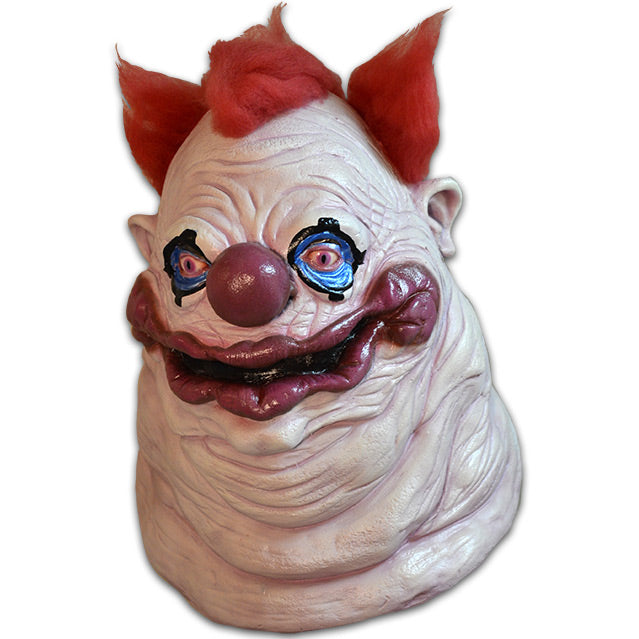 Mask, head and neck.  Lumpy and wrinkly face with several flesh folds beneath chin. White skin, 3 tufts of red hair on top and sides.  blue around eyes, outlined in black, large dark pink nose and lumpy mouth