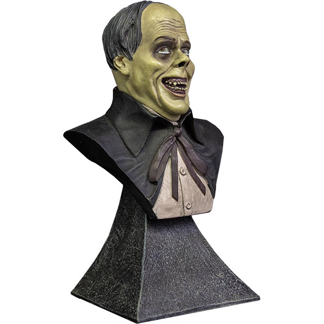 Mini bust. right side view. Phantom of the Opera Bust. Head, shoulders and upper chest of a man with balding black hair, dark circles around eyes, grinning, wearing a white shirt under a black opera cape. set on gray stone textured base.