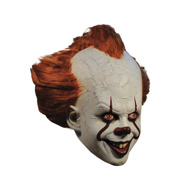 Mask, right side view. IT clown face, red hair, white cracked skin, large forehead, red eyes and nose, dark lips, creepy smile with crooked buck teeth.