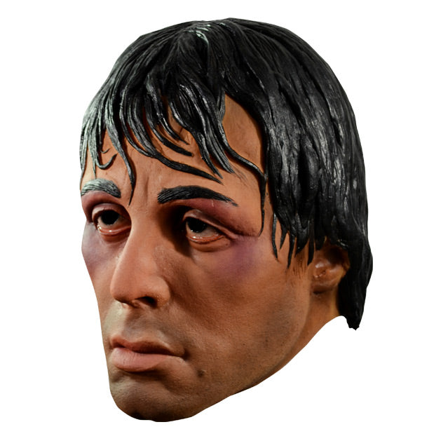 Mask, left side view. Rocky face, black hair appears wet, bruises on both eyes.