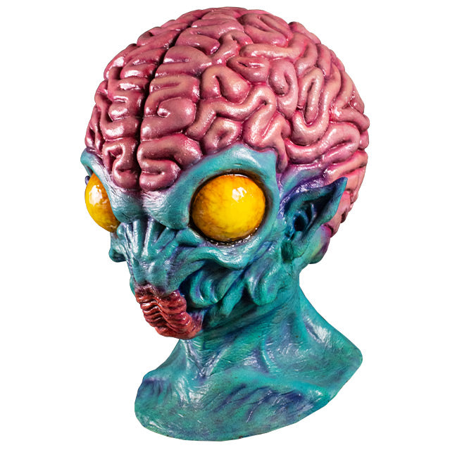 Mask, head and neck, left side view. Pink brains above forehead, blue skin on face, pointed ears. large round yellow eyes, insect-like red mouth, skin wrinkled on lower face.