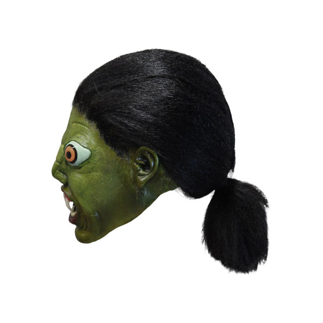 Mask, left side view. Green reptile face, long black hair pulled back in a ponytail, large orange eyes, small nose, open mouth with 2 large fangs and showing bottom teeth.