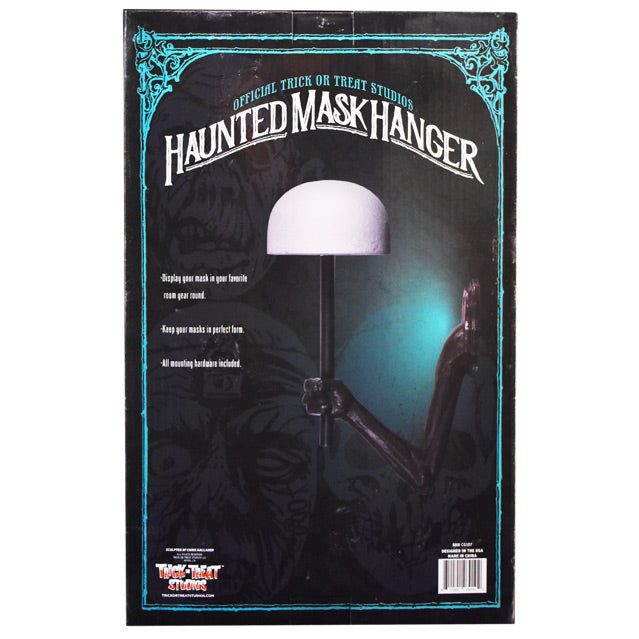Product packaging, back. Black box with blue decorative border, illustrations of three masks in background. Blue text at top reads Official Trick or Treat Studios, White text below reads Haunted Mask Hanger, display your mask in your favorite room year-round, keep your masks in perfect form, all mounting hardware included.  Manufacturing and licensing information.