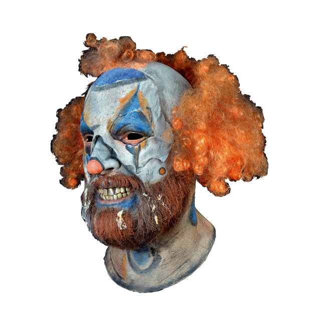Mask, head and neck, left side view. Disheveled clown mask, sparse curly red hair, white clown makeup, blue triangles painted around eyes, blue around mouth, menacing grin, beard and moustache.