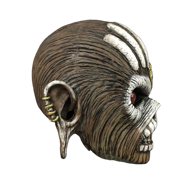 Mask, right side view. Iron Maiden Eddie, brown skin, white vertical lines on top of head, Gold embellishment in center of forehead, white paint around red eyes and across cheekbones, white painted teeth on upper and lower lips, mouth open showing teeth, stretched ears with gold studs on sides.
