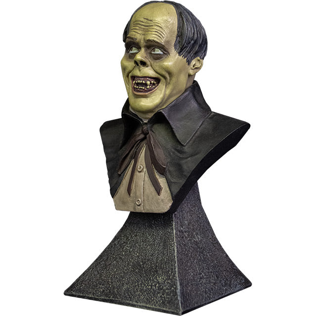 Mini bust. left side view. Phantom of the Opera Bust. Head, shoulders and upper chest of a man with balding black hair, dark circles around eyes, grinning, wearing a white shirt under a black opera cape. set on gray stone textured base.