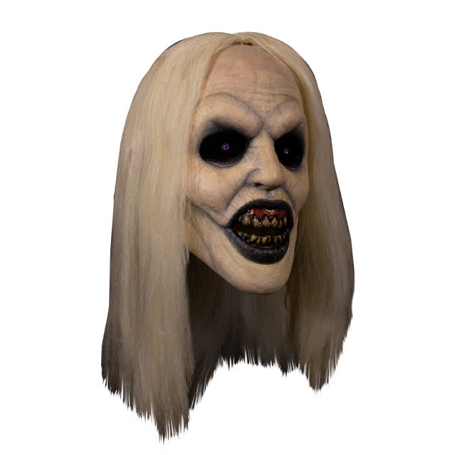 Mask, right view. Long, straight blond hair, pale skin, veins showing through. Large empty black eyes. Mouth open showing dark red gums dirty yellow teeth, black lips.