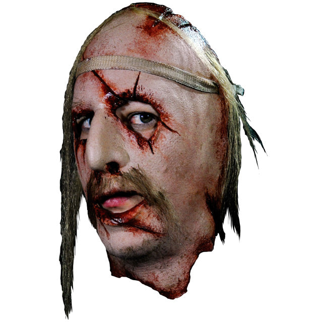 Face Mask, face and neck, left side view. Man's face, bloody with cuts and wounds around forehead, eyes, nose , mouth and neck. Sparse locks of blond hair, long blond moustache. Bandage around forehead. Shown being worn, wearer's eyes and mouth showing under mask.