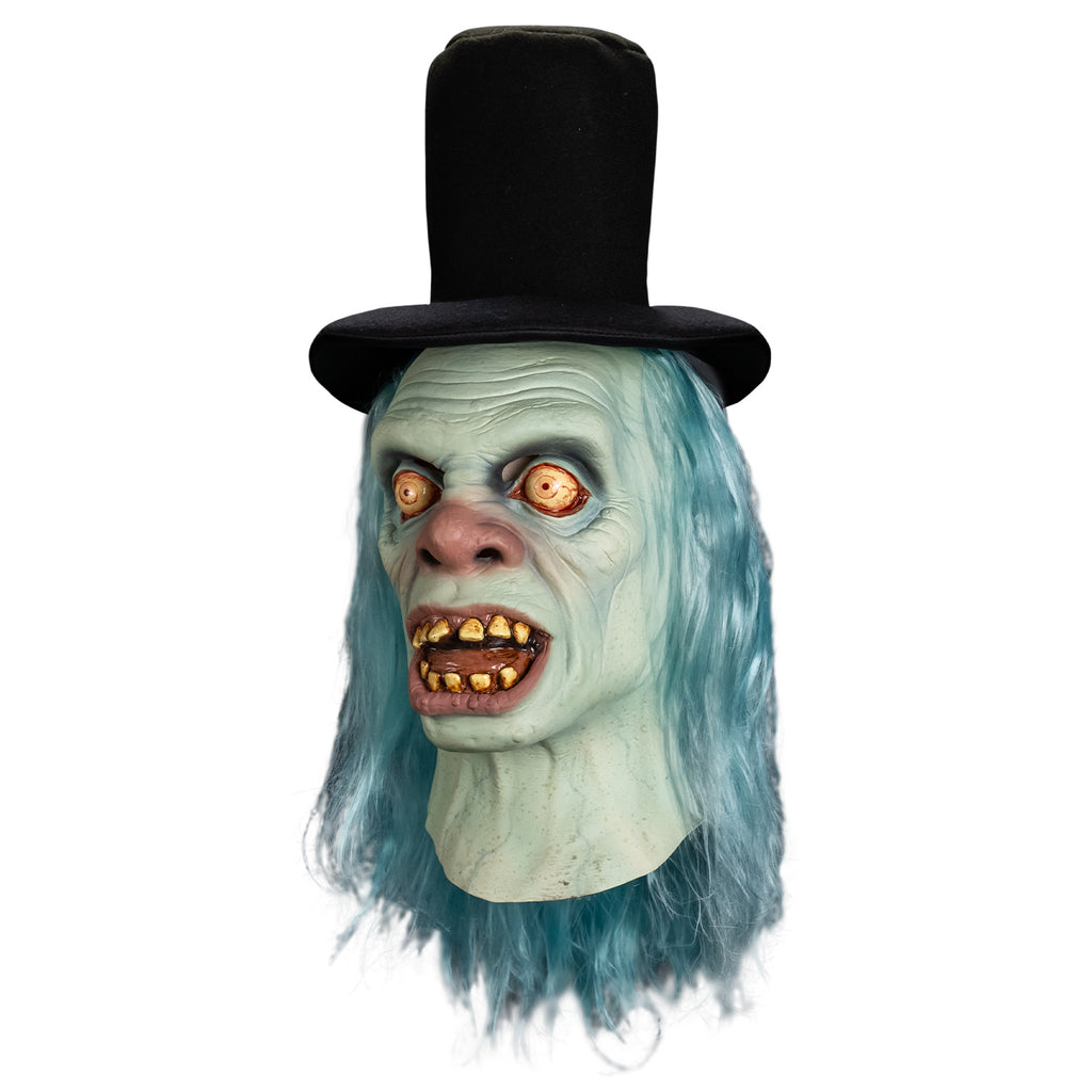 Mask left side view, head and neck. Black top hat. Long, straight, light blue hair. Pale blue wrinkled skin. No eyebrows, large, wide open, bloodshot yellow eyes. Large, bulbous pink nose. Mouth, wide open showing tongue and dirty yellowed teeth, large pink lips. blue veins showing on neck.