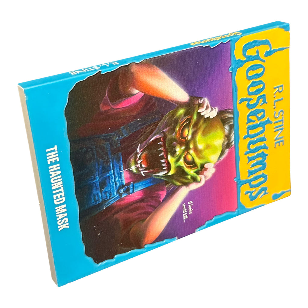 Magnet. Has the appearance of a book cover. Illustration of a child in blue overalls with a monster mask over their face, purple background. Yellow banner at top, blue text reads R.L. Stine, Goosebumps. White text on illustration reads, If looks could kill. Blue border at bottom, white text reads The Haunted mask.