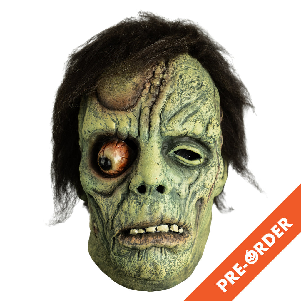 white background, orange diagonal banner bottom right, white text reads pre-order. Mask, front view. Short black hair. Greenish flesh, wrinkled and scarred. Bulging right eye. Mouth, slightly open showing bottom teeth, prominent lower lip