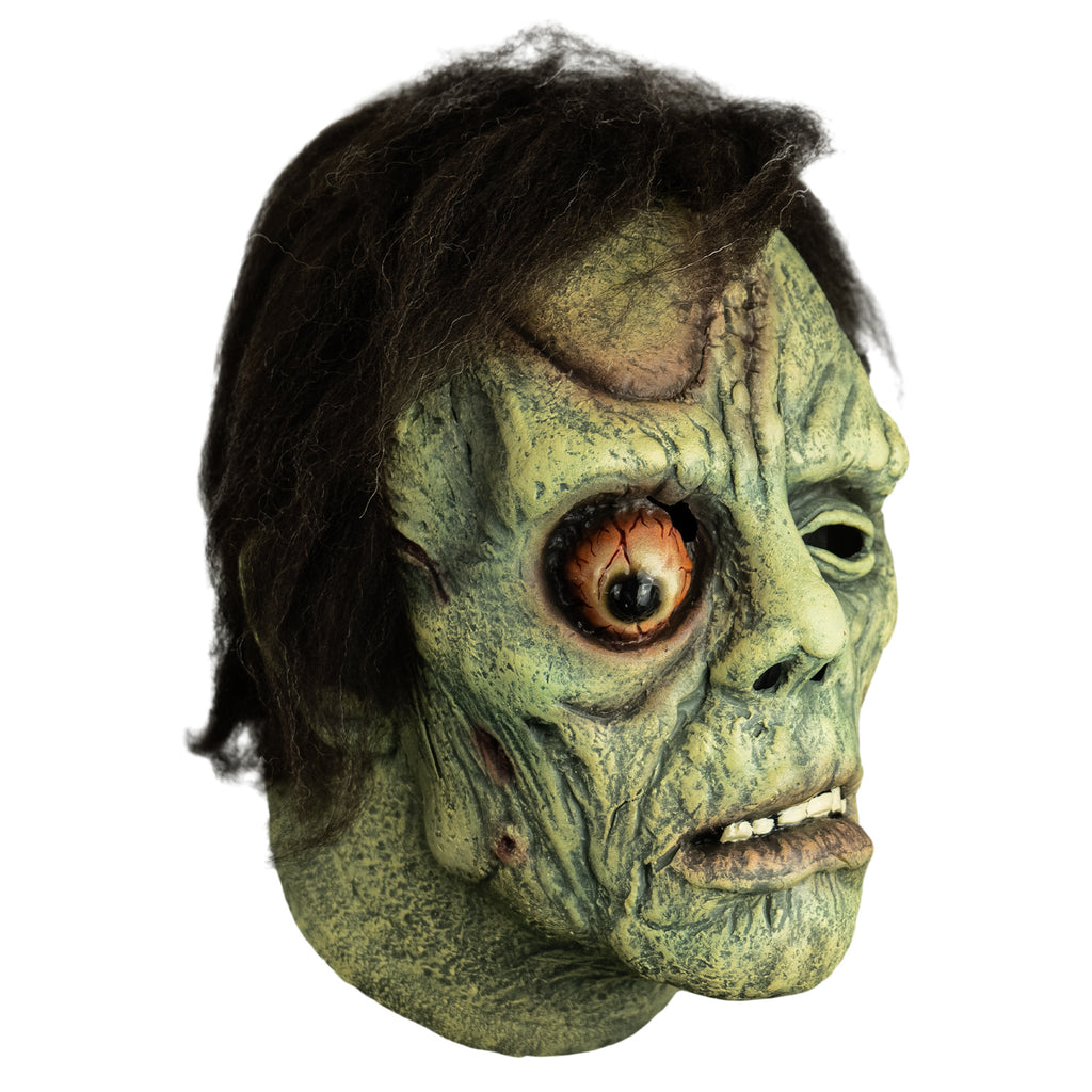 Mask, right side view. Short black hair. Greenish flesh, wrinkled and scarred. Bulging right eye. Mouth, slightly open showing bottom teeth, prominent lower lip