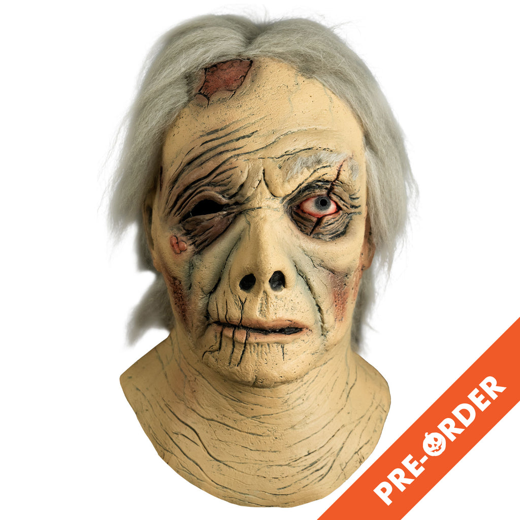 white background, orange diagonal banner bottom right, white text reads pre-order. Mask, front view. Head and neck. Short gray hair, wrinkled and ragged skin. large wound on right side of the forehead. Right eye black, no eyebrow, left eye blue, bloodshot, scar across eye. Sores on right cheekbone. Misshapen nose, mouth slightly open, thin lips.