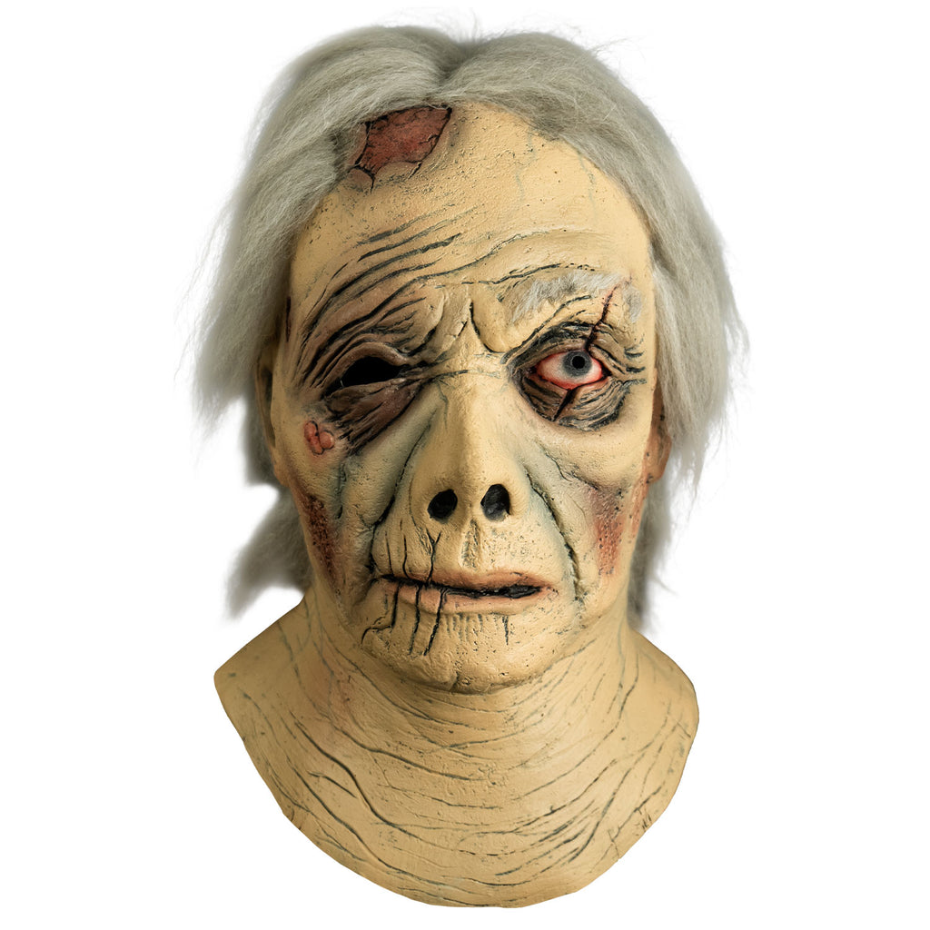 Mask, front view.  Head and neck.  Short gray hair, wrinkled and ragged skin.  large wound on right side of the forehead.  Right eye black, no eyebrow, left eye blue, bloodshot, scar across eye.  Sores on right cheekbone.  Misshapen nose, mouth slightly open, thin lips.