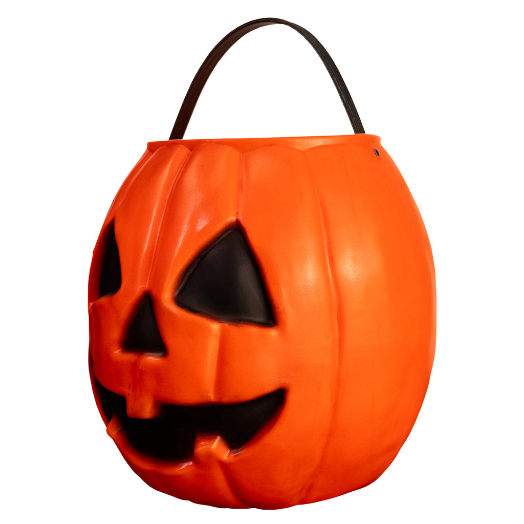left view pumpkin candy pail. Orange Jack o' lantern face. black eyes nose and face. Black handle at top.