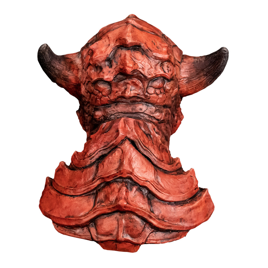 Mask, back view. Red creature with horns on either side of head, wrinkled and scaly skin. Large plate-like scales on back of head, neck and chest