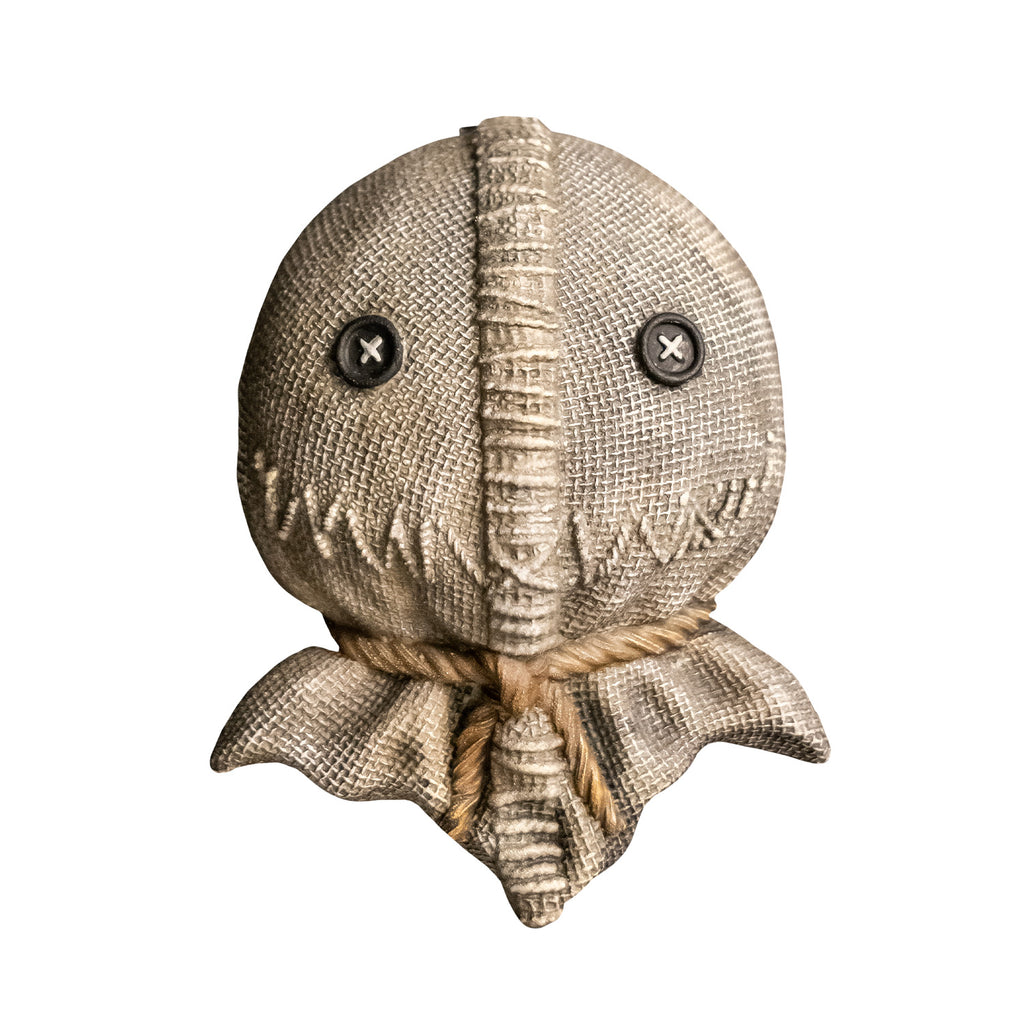 Magnet.  Trick 'r Treat Sam. Burlap sack scarecrow-like face, black button eyes, stitched down center of face, zigzag stiches for mouth, cord at neck.