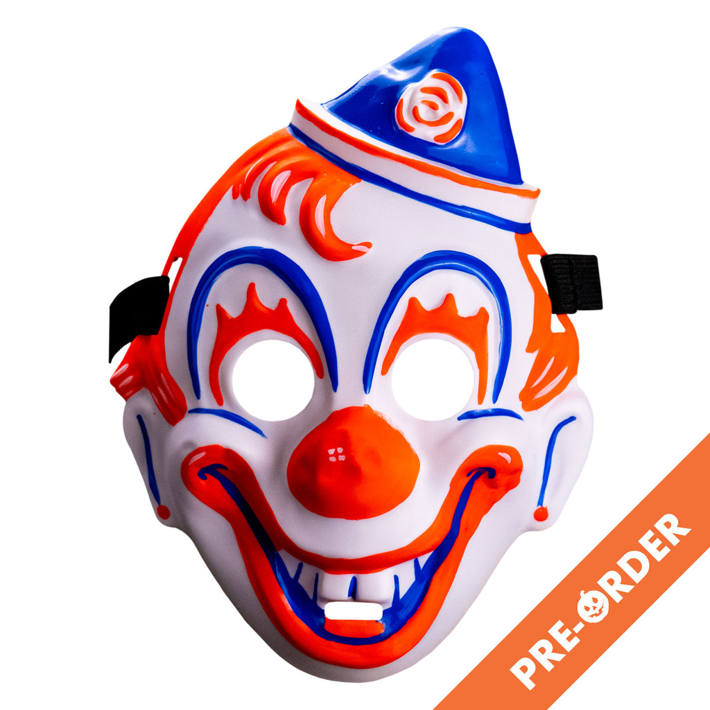 White background, orange diagonal banner bottom right, white text reads pre-order. Face mask, front view. white clown face, blue white and orang triangular hat tipped to the left . orange painted hair. Blue arches around eyes, orange painted eyelashes, blue lines on cheeks and ears, orange dots on earlobes, large orange clown nose. Orange and blue clown mouth in a large smile showing teeth. Black elastic strap at temples