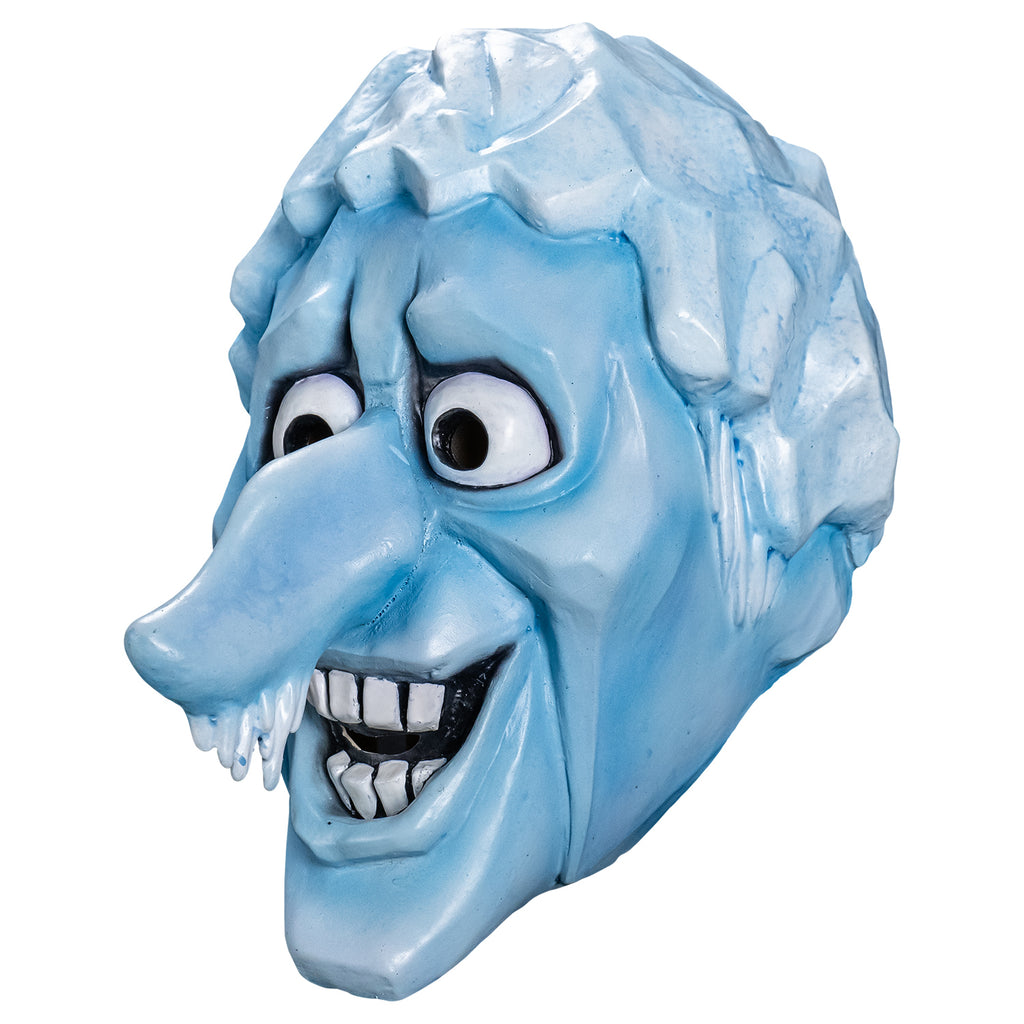 Mask, left side view. Cartoonish head, pale blue angular ice-like hair, icicles for sideburns, skin is light blue, furrowed brow, no eyebrows, large cartoon eyes, very long prominent nose with icicles hanging from the tip, angular forehead, cheeks and chin. open, smiling mouth showing large square white teeth.