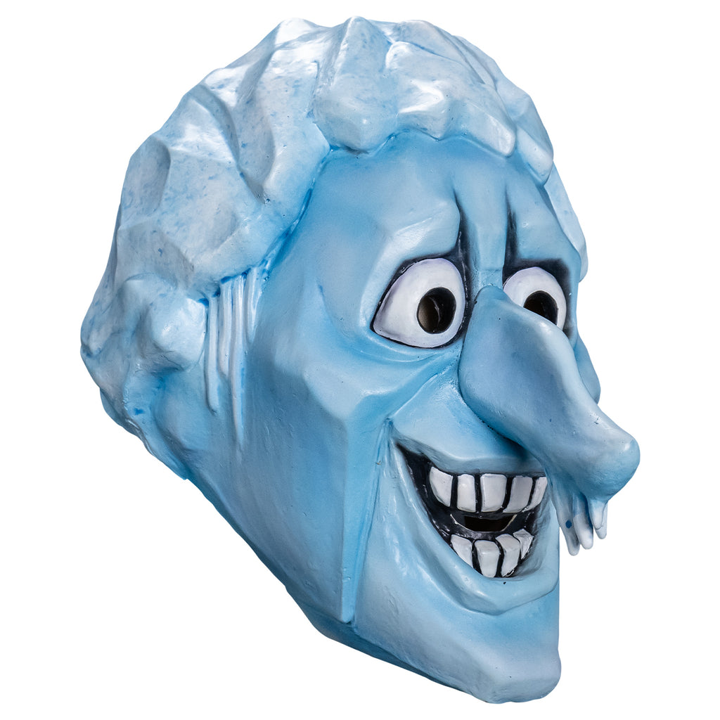 Mask, right side view. Cartoonish head, pale blue angular ice-like hair, icicles for sideburns, skin is light blue, furrowed brow, no eyebrows, large cartoon eyes, very long prominent nose with icicles hanging from the tip, angular forehead, cheeks and chin. open, smiling mouth showing large square white teeth.