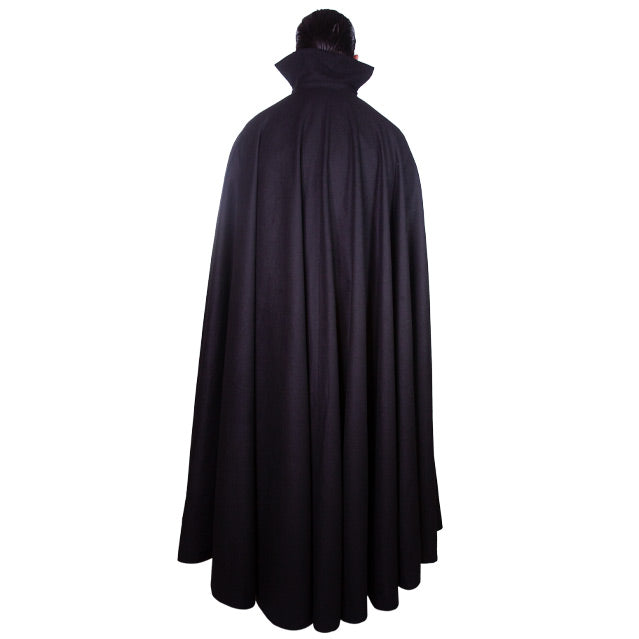Back view.  Man wearing floor length black cape.  Cape has standing collar.