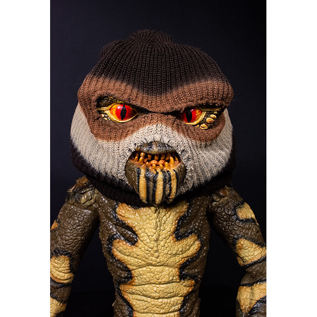 Gremlin Puppet, closeup view of face and chest. Orange eyes, sharp teeth, black claws on hands and feet. Wearing brown, white and black ski mask.