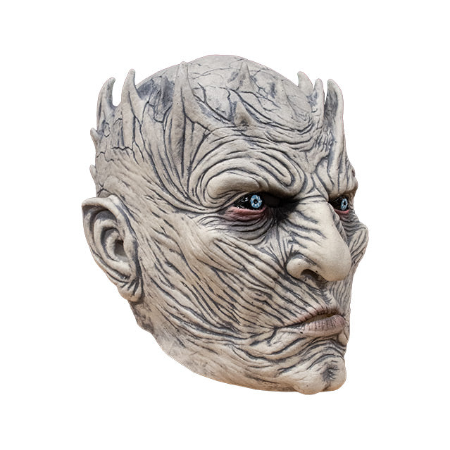 Right side view. Night King Mask. Bald head, extremely wrinkled light gray skin, spikes around crown of head. Bright blue red-rimmed eyes on black where the whites should be.