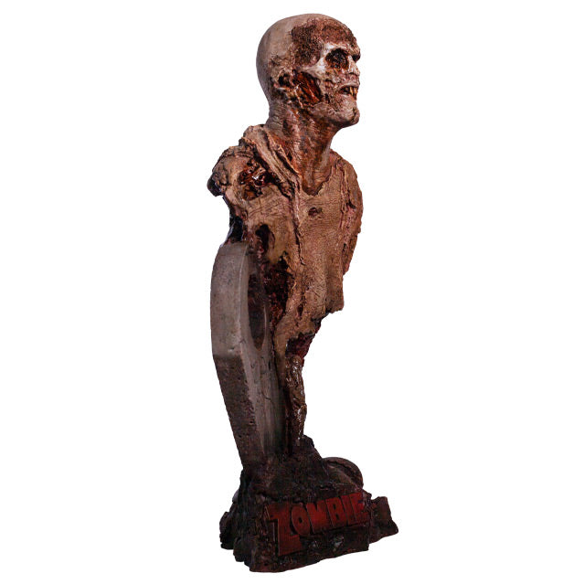 Bust, front right side view. Rotted zombie head neck and upper torso, wearing dirty rotted torn clothing. Gore around shoulders and bottom of torso. Face has rotting flesh, black eyes, mouth of jagged dirty teeth. Base is gravestone set in soil, with zombie arm coming from the ground , plaque at bottom with red text reading Zombie.