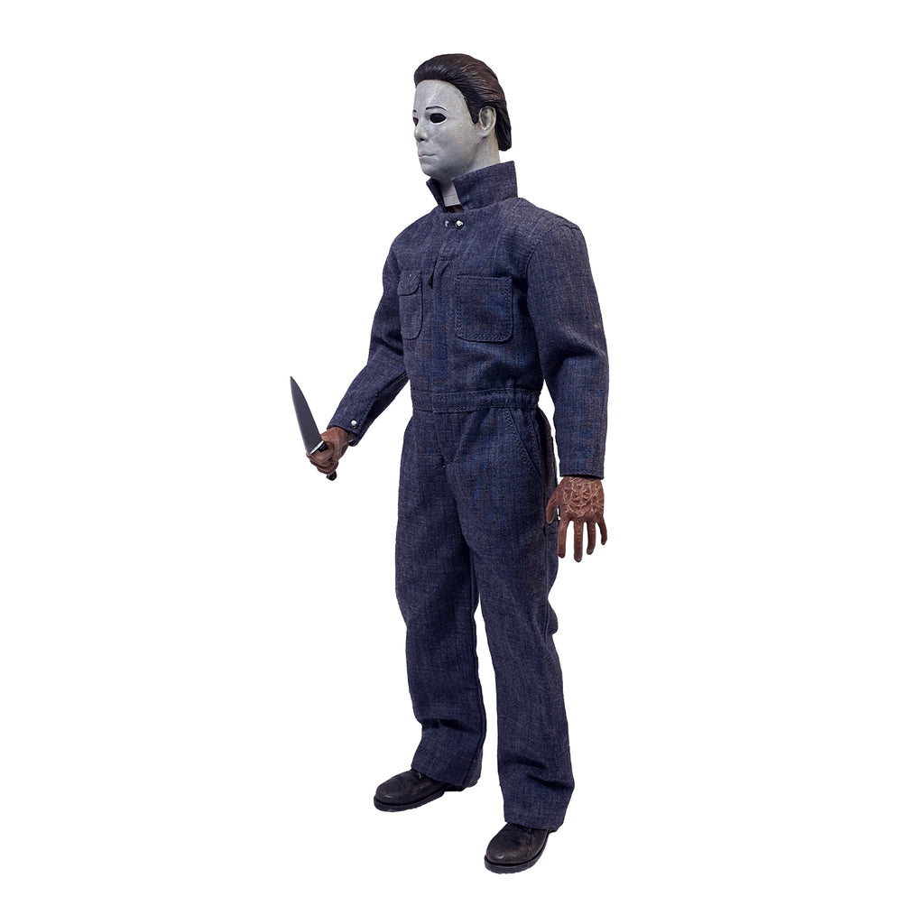 Left side view. Halloween 4 Michael Myers 12" figure. White mask brown hair, wearing blue coveralls, black boots, holding butcher knife in right hand.