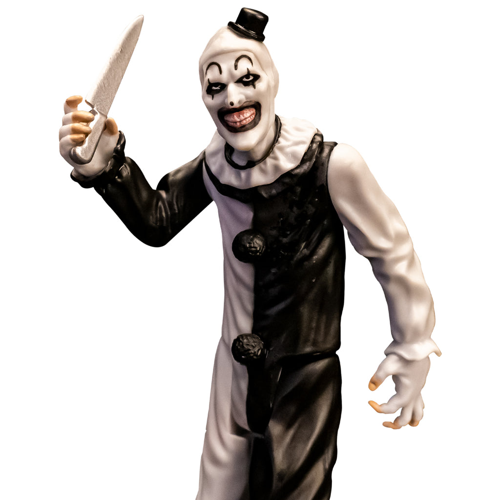 Terrifier, 5 inch figure, close up. Evil grinning clown face with tiny black top hat, black and white, jumpsuit, ruffle at neck, fingerless white gloves holding kitchen knife in right hand.