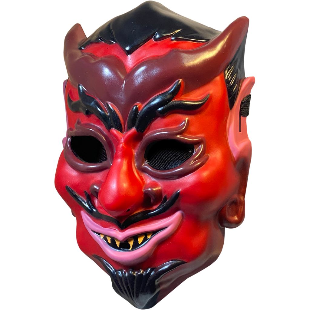 Plastic mask, left side view. Red devil face, black hair, eyebrows, moustache and goatee. Maroon horns, outlines around eyes, nostrils and earlobes. Pink upper ears and lips. Pointed yellow teeth.