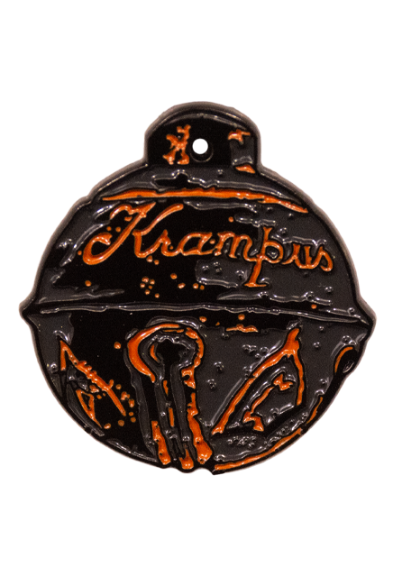 Enamel pin.  Sleigh bell, black with copper colored decorations, cursive writing reads Krampus.