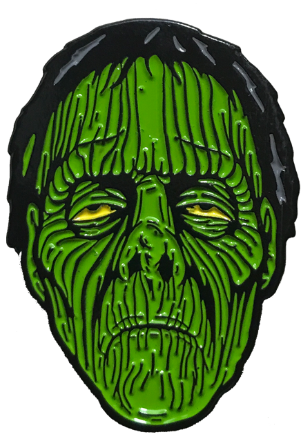 Enamel pin, zombie face, wrinkled green flesh, yellow eye, black hair.