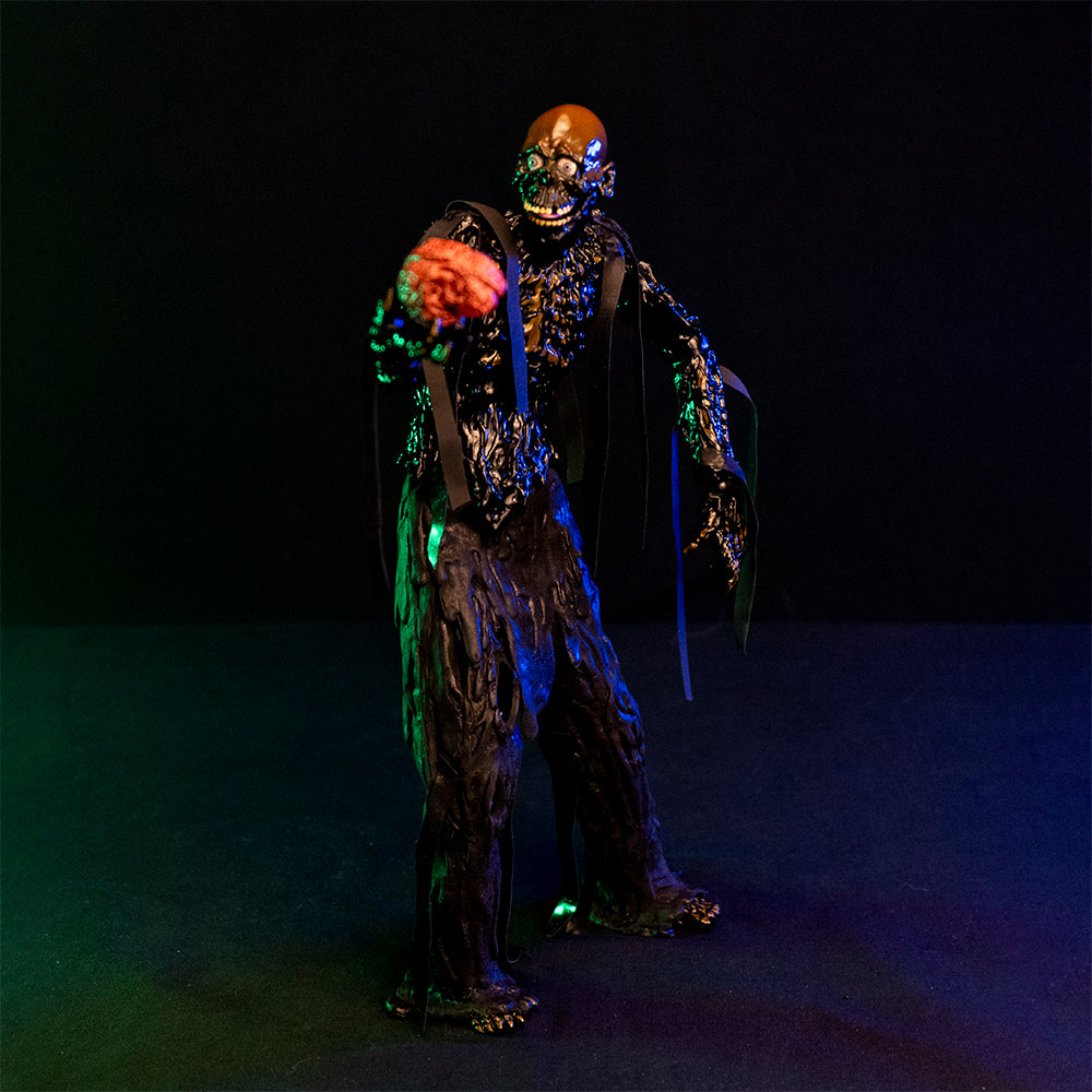 1/6 scale Tarman figure, slight right view.  Bare skull, grinning mouth, tar covered body, ribs showing through dripping tar. Holding a pink brain in his right hand