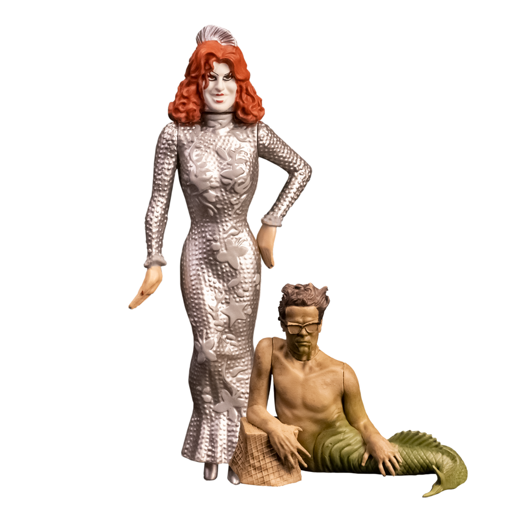2 action figures, front view.  Showtime Baby Firefly, woman with red hair, pale makeup, wearing long sleeved floor length silver dress.  Fishboy, merman with short brown hair, glasses, green fish tail, resting right arm on brown stone.