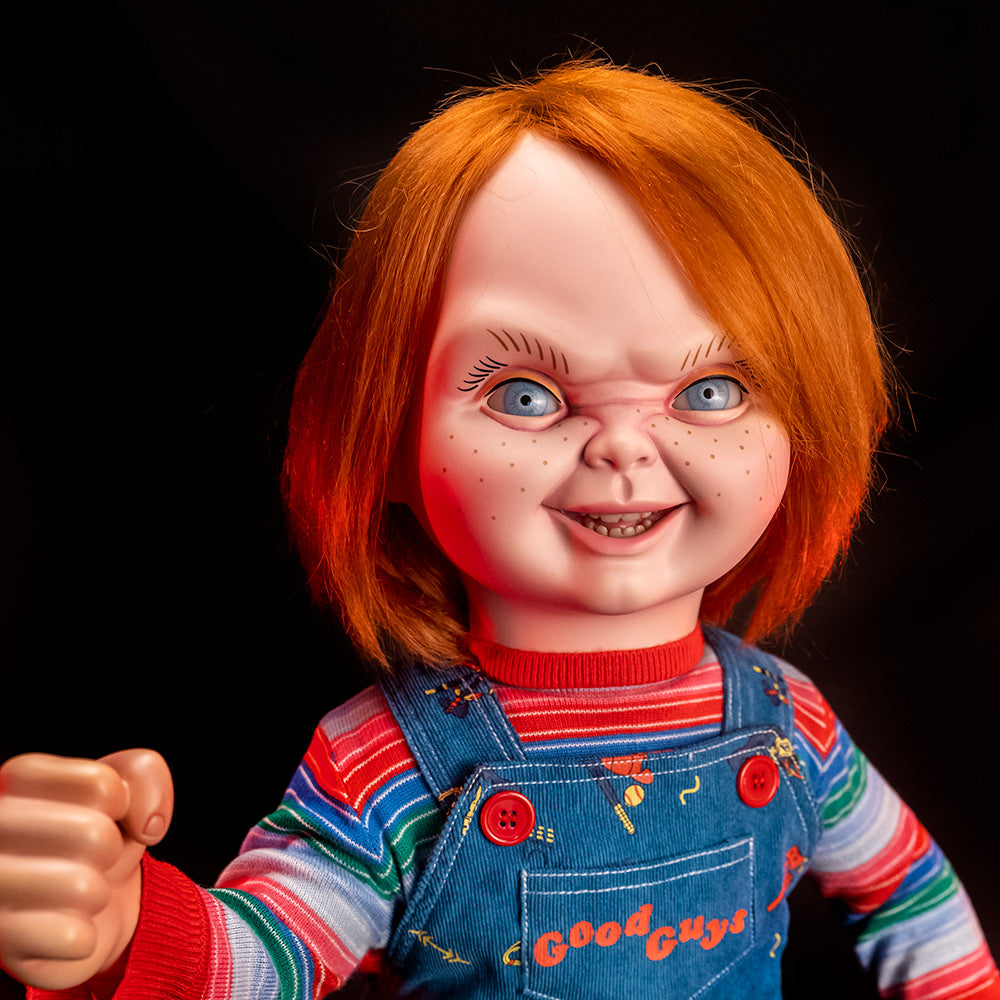Ultimate Chucky Doll close up of face and chest. Red hair, blue eyes, freckles, cleft chin. Face sneering. Right hand raised in fist.
