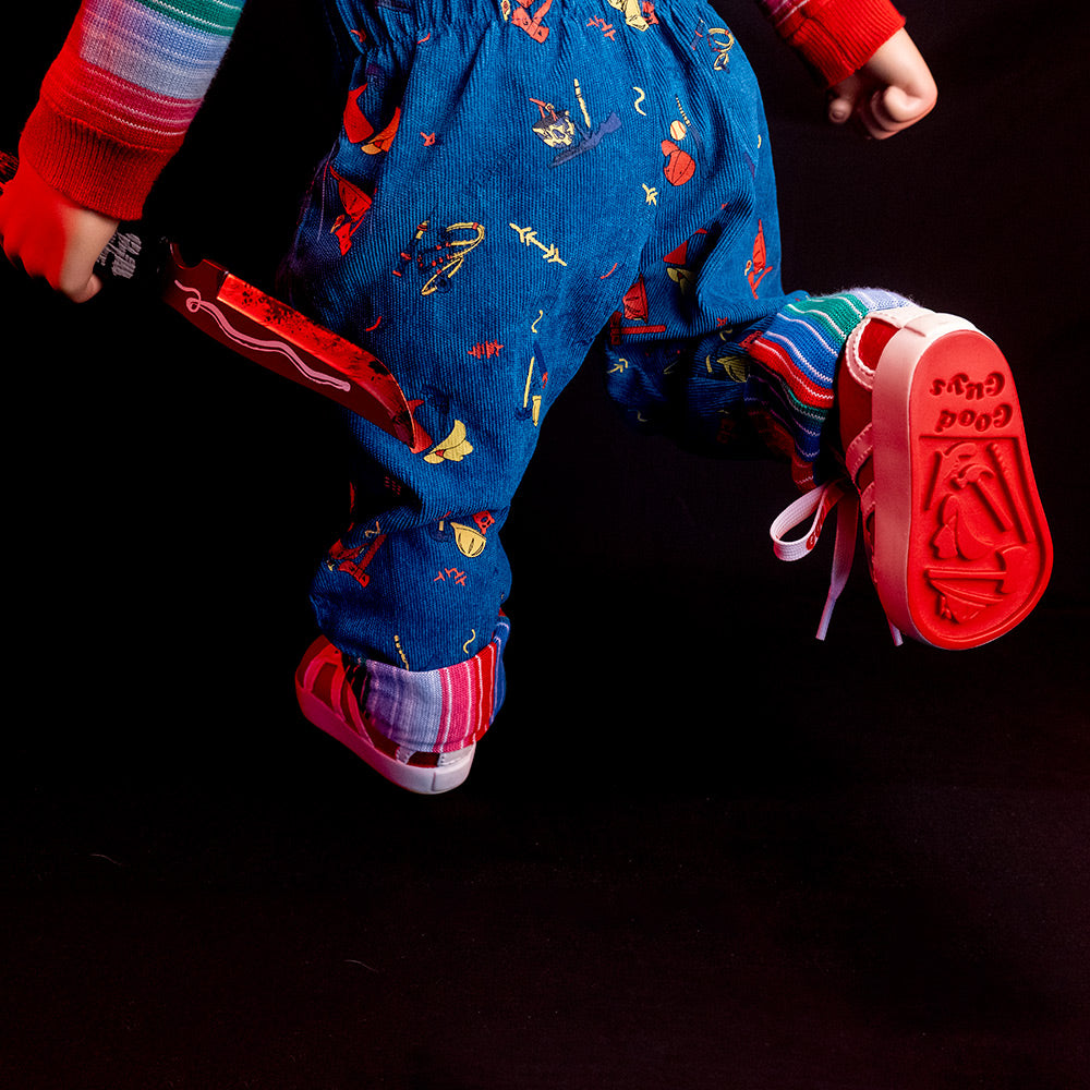 Rear view of doll, below waist, holding knife in left hand. Close up of detail of bottom of sneaker, red, text reads Good Guys.
