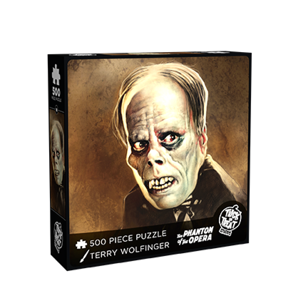 product box, front.  illustration of the phantom of the opera. Dark gray hair, pale wrinkled skin on face and neck, dark circles around eyes, snub nose, mouth grimacing, prominent dark gums and large yellowed teeth.  white text at bottom reads 500 piece puzzle, Terry Wolfinger, The Phantom of the Opera.  white trick or Treat Studios logo bottom right