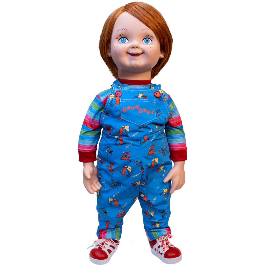 Plush body Good Guy doll.  Red hair, blue eyes, freckles, cleft chin.  Wearing red, white, green and blue striped shirt under blue overalls, red buttons, red printed text reads Good Guys on front pocket, red and white sneakers.