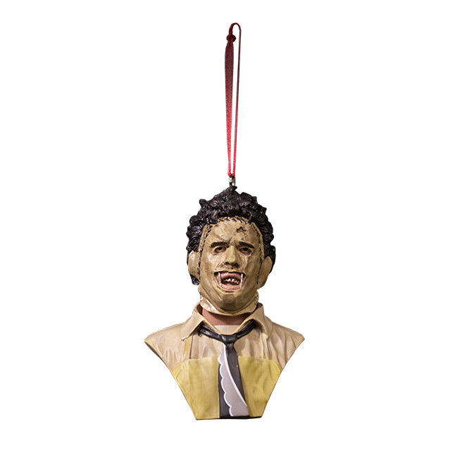 Ornament. Front view. Leatherface Bust. Head, shoulders and upper chest of a man wearing a stitched together human face mask, black hair.  Wearing a tan shirt with a black and white necktie, yellow apron.
