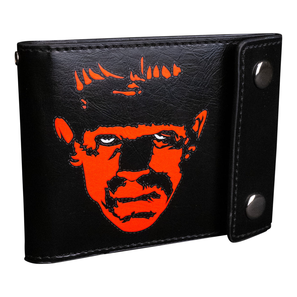 Wallet, front closed view. Black, 2 silver snaps, black and red-orange illustration of Frankenstein face, white eyes
