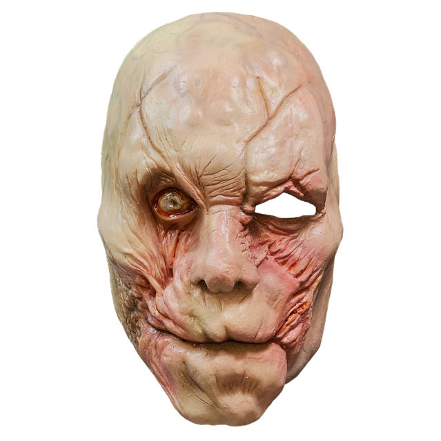 Plastic face mask.  Bald, pink flesh toned skin, scarred and deformed to appear that skin was grafted on.  Milky right eye, open eye hole for left eye.  Mouth has no lips.