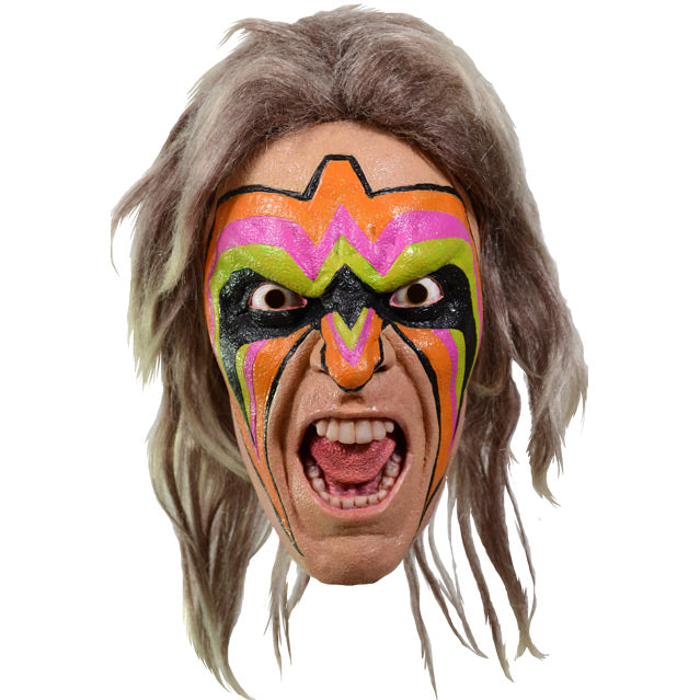 Mask, front view.  Long ash blond hair.  Angry male face, mouth open in a yel showing teeth and tongue.  Orange, pink, bright green, and black face paint on forehead, eyes, nose and cheeks.