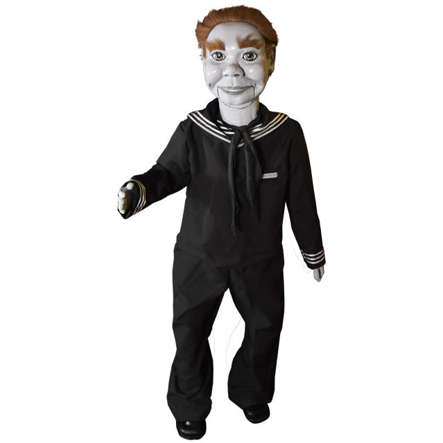 Prop. Ventriloquist dummy, white face and hands, light brown hair and bushy eyebrows, wearing black coveralls, white stripes at neck and cuffs, black shoes.