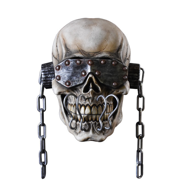 Mask, front view.  Skull wearing metal eye covering with rivets, ear covers with chains hanging off of them, four silver metal hooks attached above to below teeth.