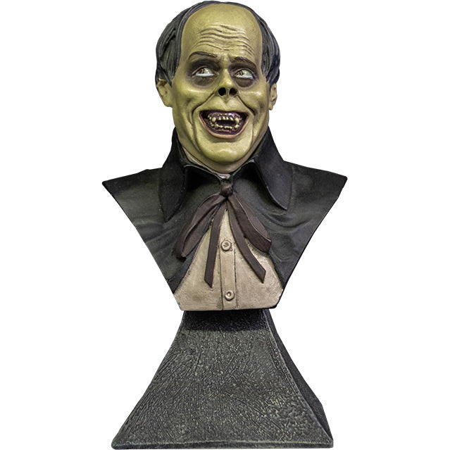 Mini bust. Front view. Phantom of the Opera Bust. Head, shoulders and upper chest of a man with balding black hair, dark circles around eyes, grinning, wearing a white shirt under a black opera cape. set on gray stone textured base.